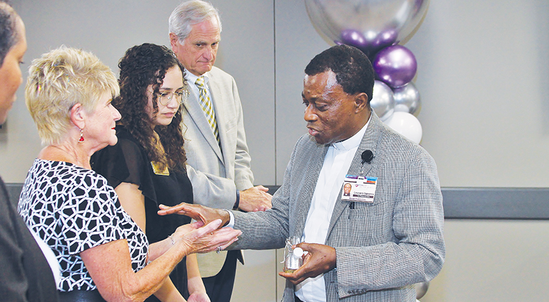 Fr. Leonard Ogbonna, manager of spiritual care with CHRISTUS Health anoints the hands of representatives of nonprofit partners of the system.