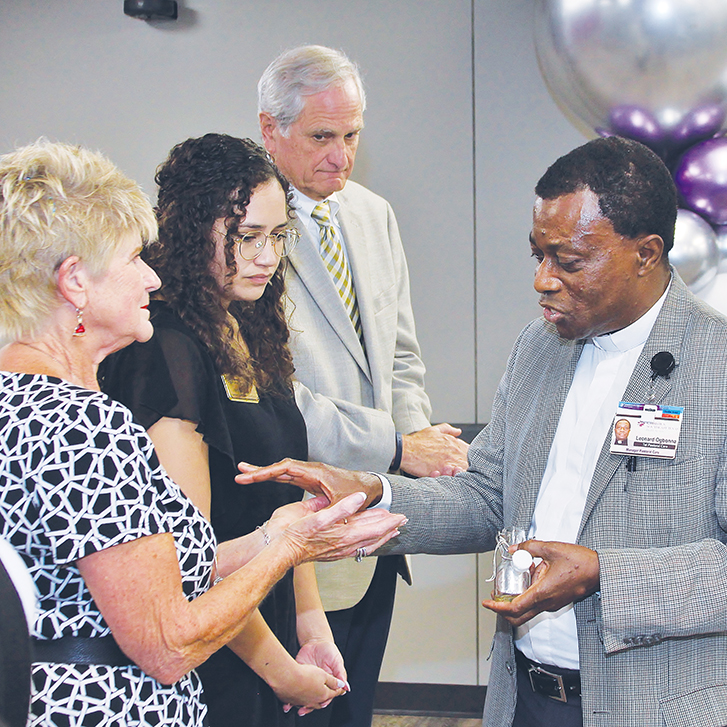 Fr. Leonard Ogbonna, manager of spiritual care with CHRISTUS Health anoints the hands of representatives of nonprofit partners of the system.