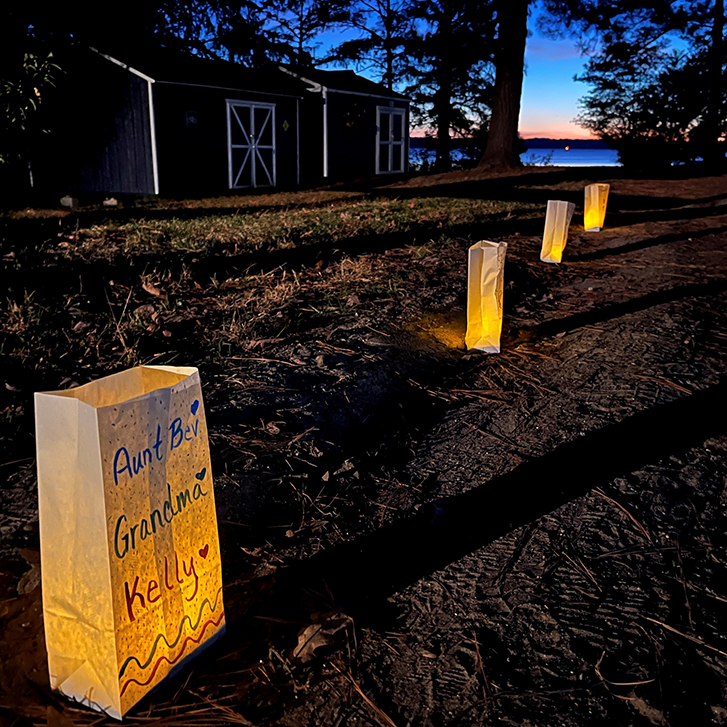 Luminarias with names of deceased family members line a walkway at Mikey’s Camp, a part of a program called KIDZ’NGRIEF.