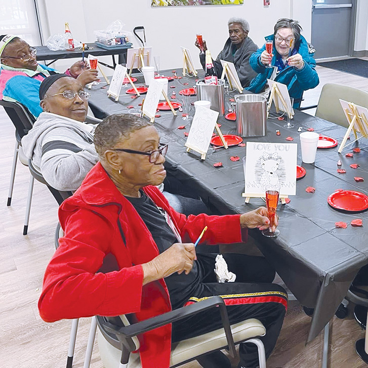 Participants at Trinity Health PACE Alexandria in Louisiana enjoy each other’s company during a Valentine’s Day painting activity.